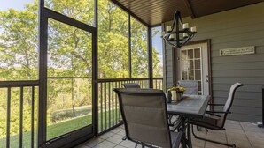 Un patio techado con mesa y sillas, ventanas grandes y un cartel en la pared.