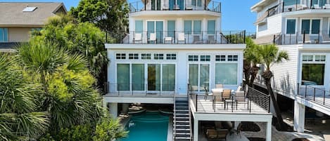 A multi-level residential property with a swimming pool, outdoor seating, and lush landscaping.
