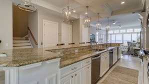 A spacious kitchen with granite countertops, white cabinetry, and pendant lighting. - 28 Carters Manor- Oceanfront Compound, Two Private Pools (Hilton Head Island)