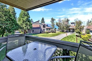 Ein Balkon mit Glastisch und Stühlen, der auf ein Wohngebiet mit Häusern und einem wolkenlosen Himmel blickt.