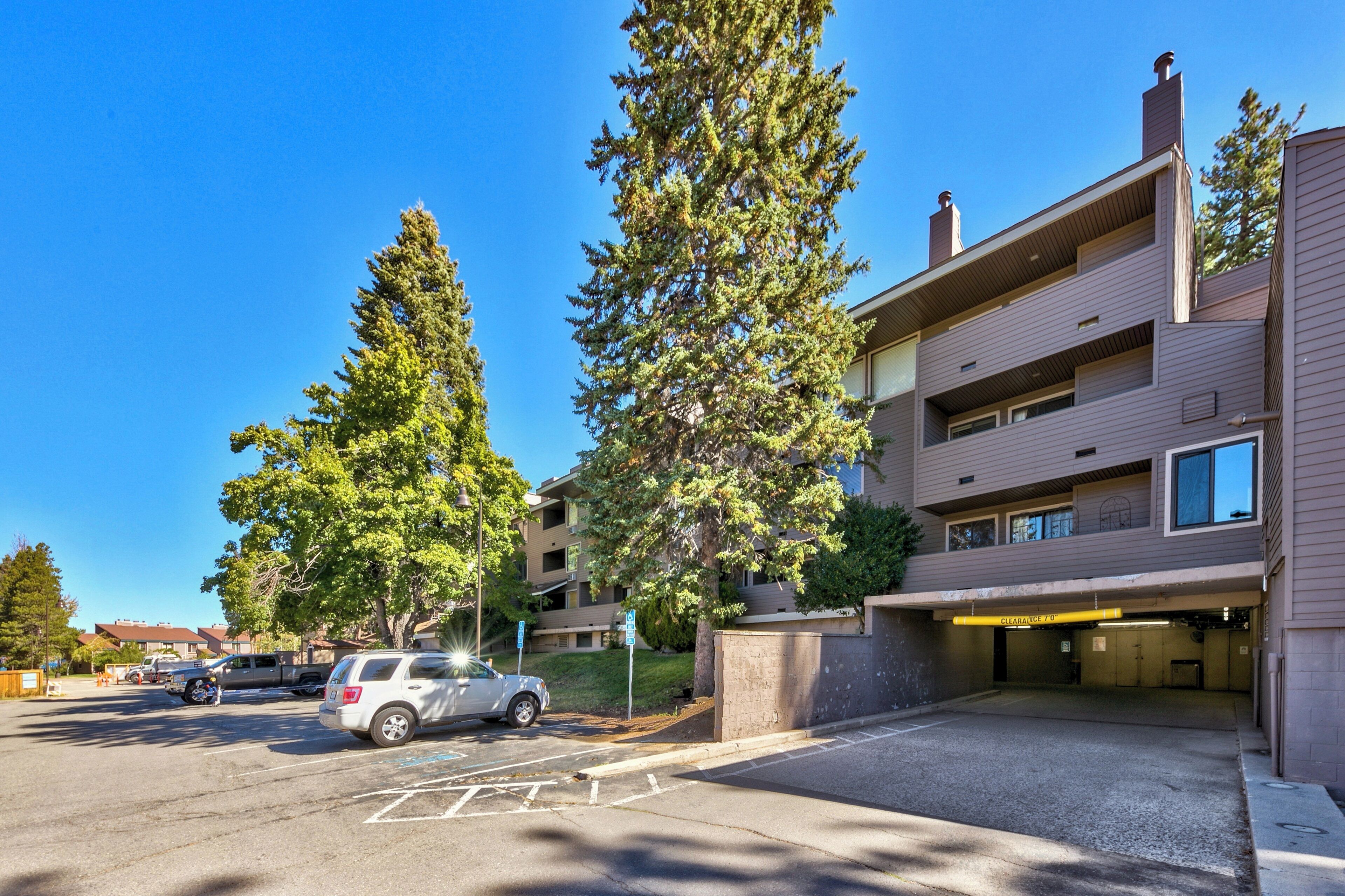 A multi-story parking garage with a covered entrance, adjacent to a building with a flat roof and large windows.