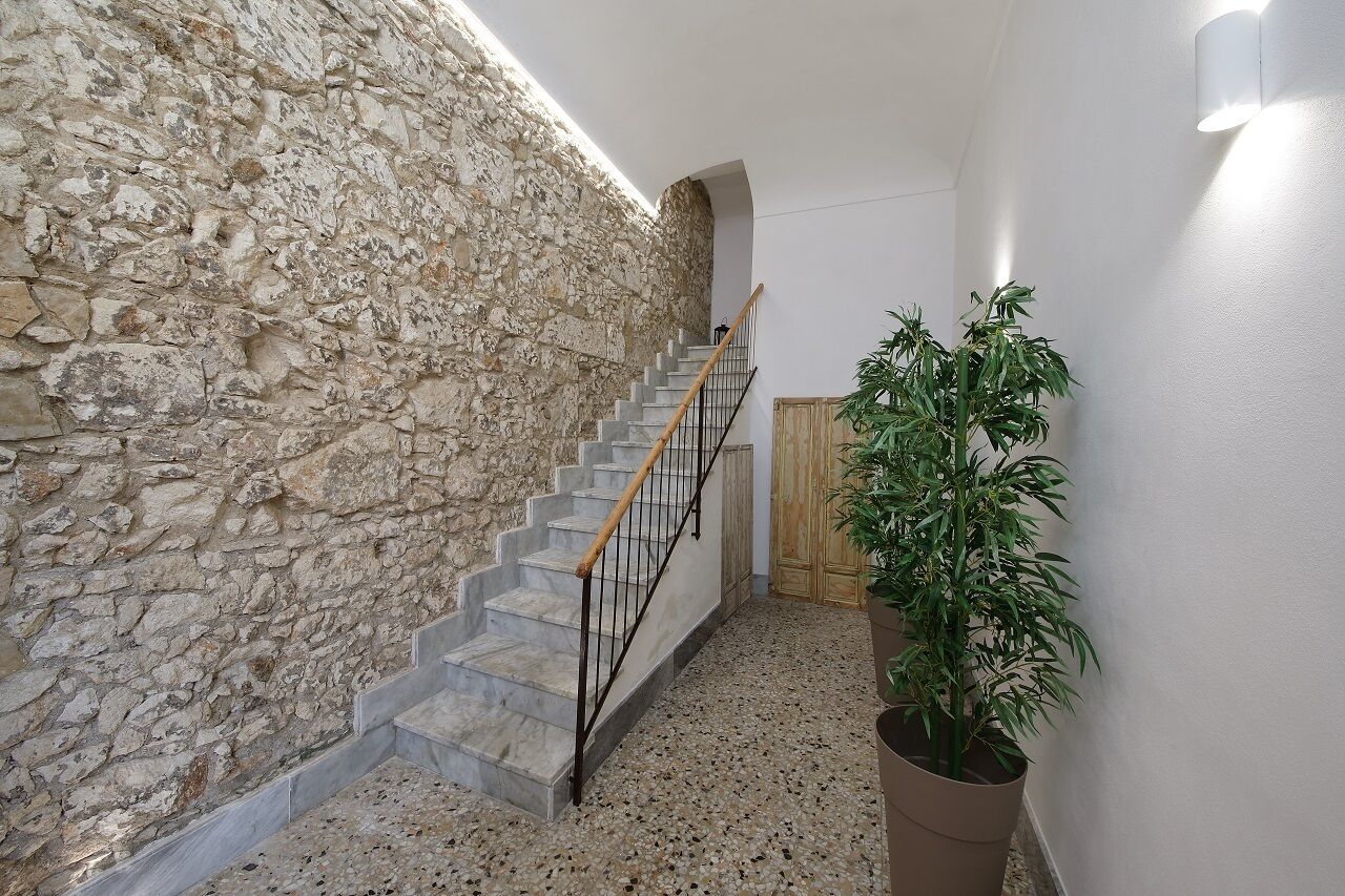 Un escalier avec un mur en pierre d’un côté et un pot de fleurs de l’autre.