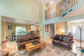 Relax in this spacious living area with a high ceiling, featuring a comfortable sofa set, dining table, and kitchen area.