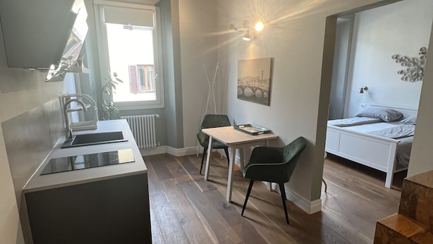 A compact room with a kitchenette, a dining area, and a bed.