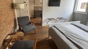 A modern bedroom with a bed, a chair, a desk, and a TV.