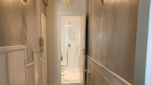 A hallway with wooden flooring, white walls, and a brick archway.