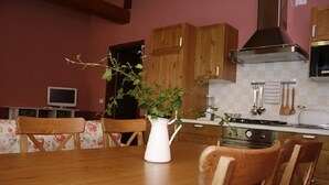 A kitchen with wooden cabinets, a stove, and a dining table with chairs. - "Particolari del Brenta" - Elisa accommodation - Comfortable house with garden in Venice (Mira)