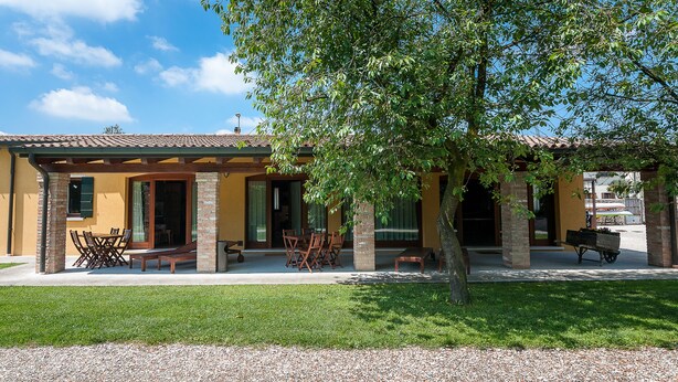 A yellow building with a patio area, outdoor seating, and a tree. - "Particolari del Brenta" - Elisa accommodation - Comfortable house with garden in Venice (Mira)