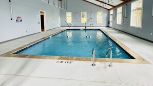 Ein Hallenbad mit klarem Wasser, einem Rettungsschwimmer-Schild und einer Tür zu einem anderen Raum.