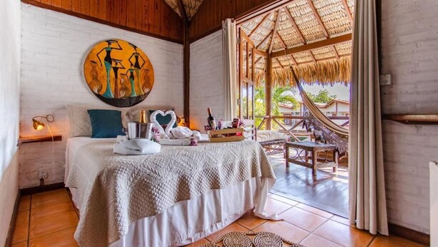 Un dormitorio acogedor con una cama, un cuadro y vistas a un espacio exterior con una hamaca.