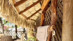 Una estructura de madera con toallas colgando y una cesta tejida.