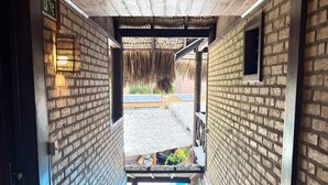 Una escalera conduce a una zona de piscina con techo de paja y paredes de ladrillo.