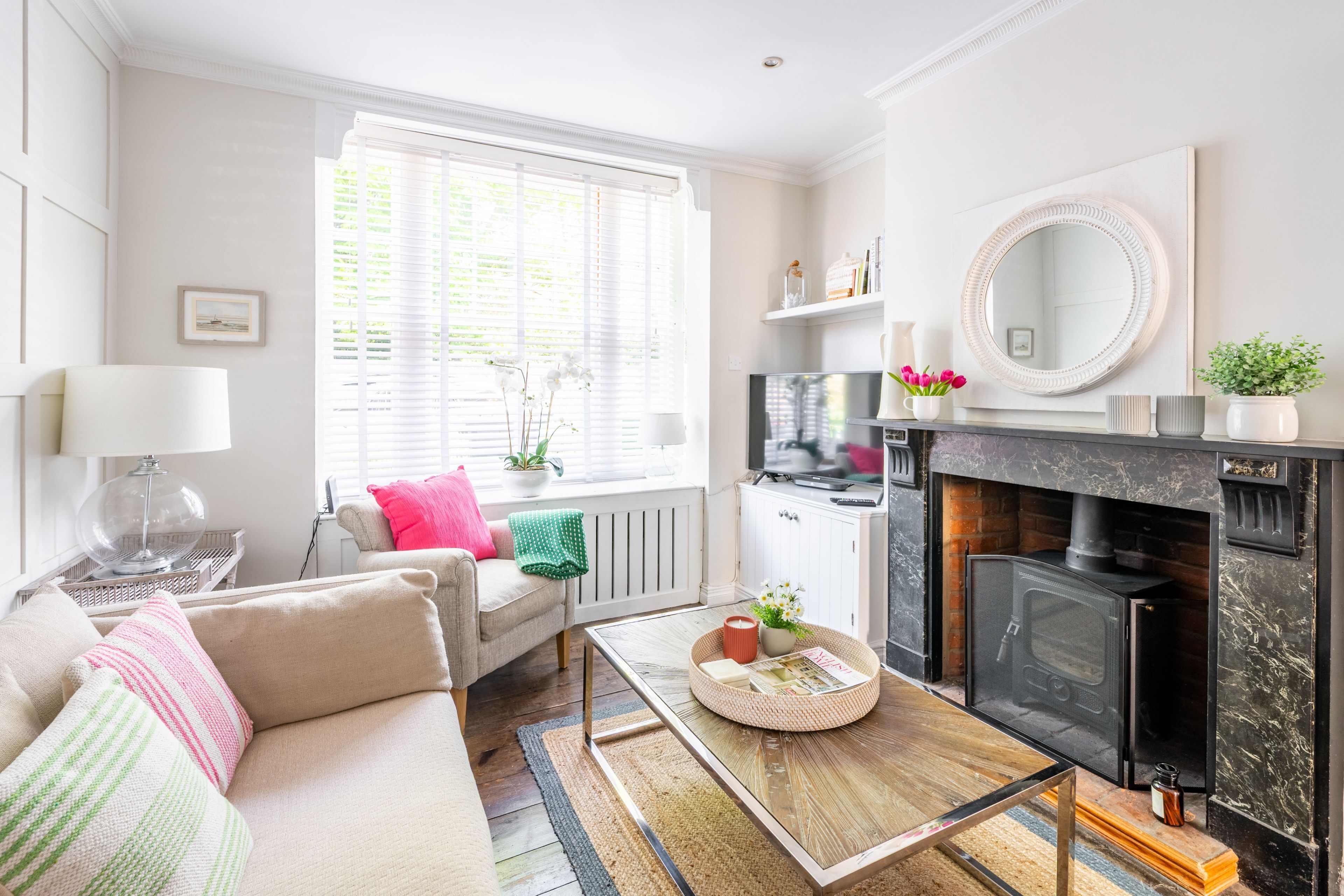 A living room with a sofa, coffee table, fireplace, and a television.