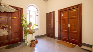A hallway with wooden doors, a potted plant, and a window. - CODY'S APARTMENT - HOLIDAY HOME IN ROME  (Roma)