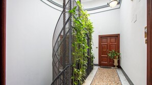 A hallway with a metal spiral staircase, a wooden door, and a potted plant. - CODY'S APARTMENT - HOLIDAY HOME IN ROME  (Roma)