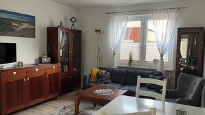 Una sala de estar con televisor, mueble de madera, sofá y una mesa de comedor.