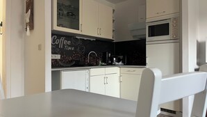 Una cocina moderna con gabinetes blancos, un diseño con motivos de café y un microondas.