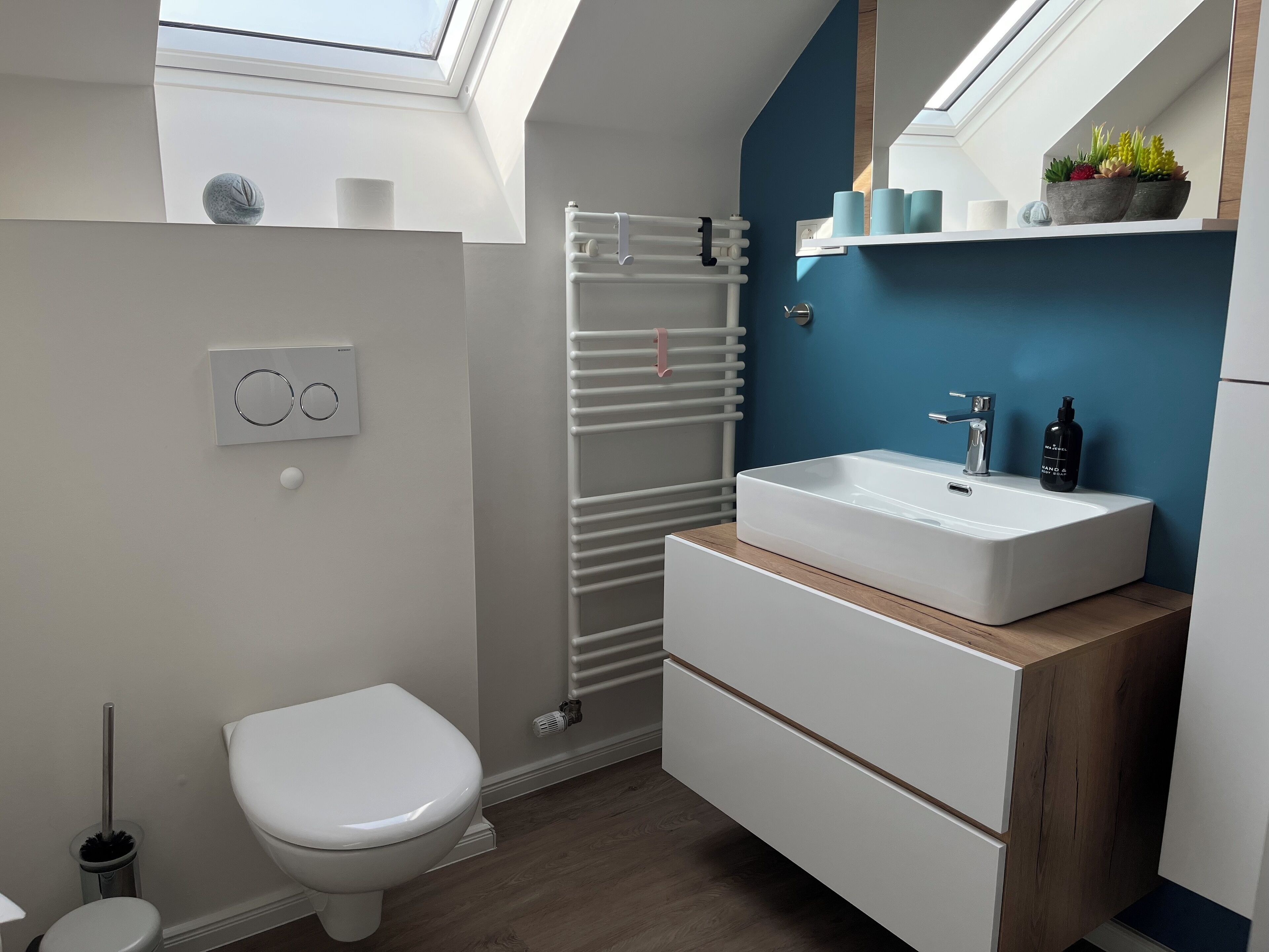 A modern bathroom with a skylight, white toilet, white sink, and a towel rack.