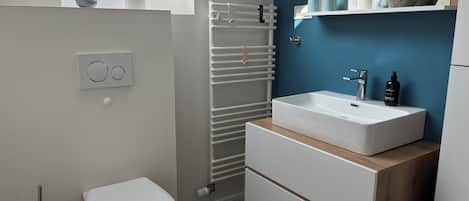 A modern bathroom with a skylight, white toilet, white sink, and a towel rack.