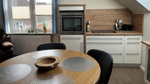 Una cocina moderna con horno integrado, tostadora y ventana con cortinas.