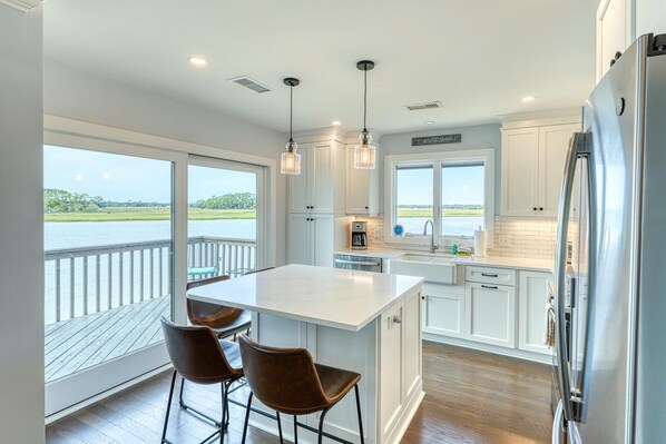 A modern kitchen with a large island, white cabinetry, and a view of the water.
