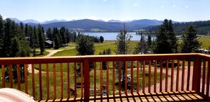 Eine Holzterrasse mit Blick auf einen See, Berge und einen bewaldeten Bereich.