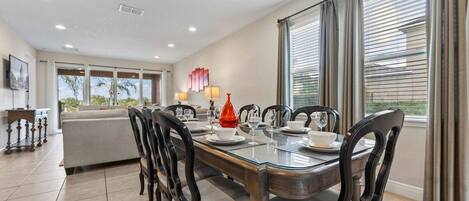 A dining area with a glass-top table, dark chairs, and a red decorative object.