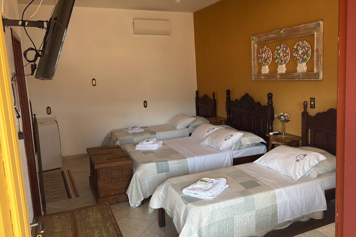 A hotel room with two beds, a wooden nightstand, a small table, and a wall-mounted air conditioner.
