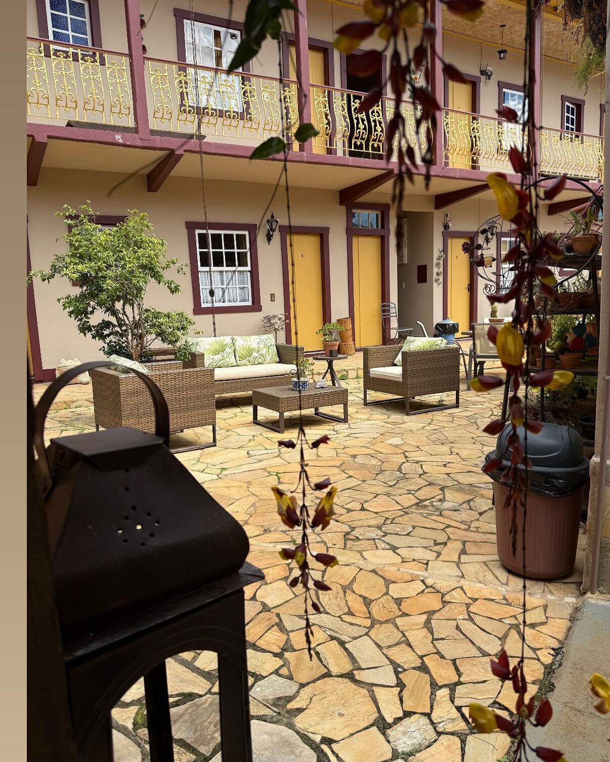 A courtyard with wicker furniture, potted plants, and a stone floor.