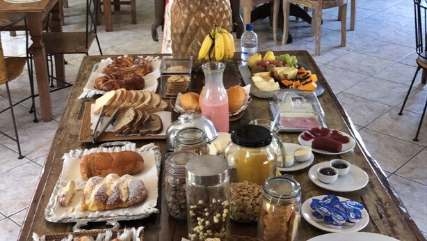 Un bufé de desayuno con diversos pasteles, frutas y bebidas sobre una mesa de madera.