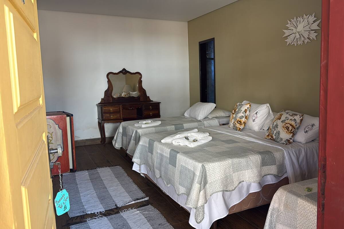 A room with two beds, a wooden dresser, a mirror, and a door.