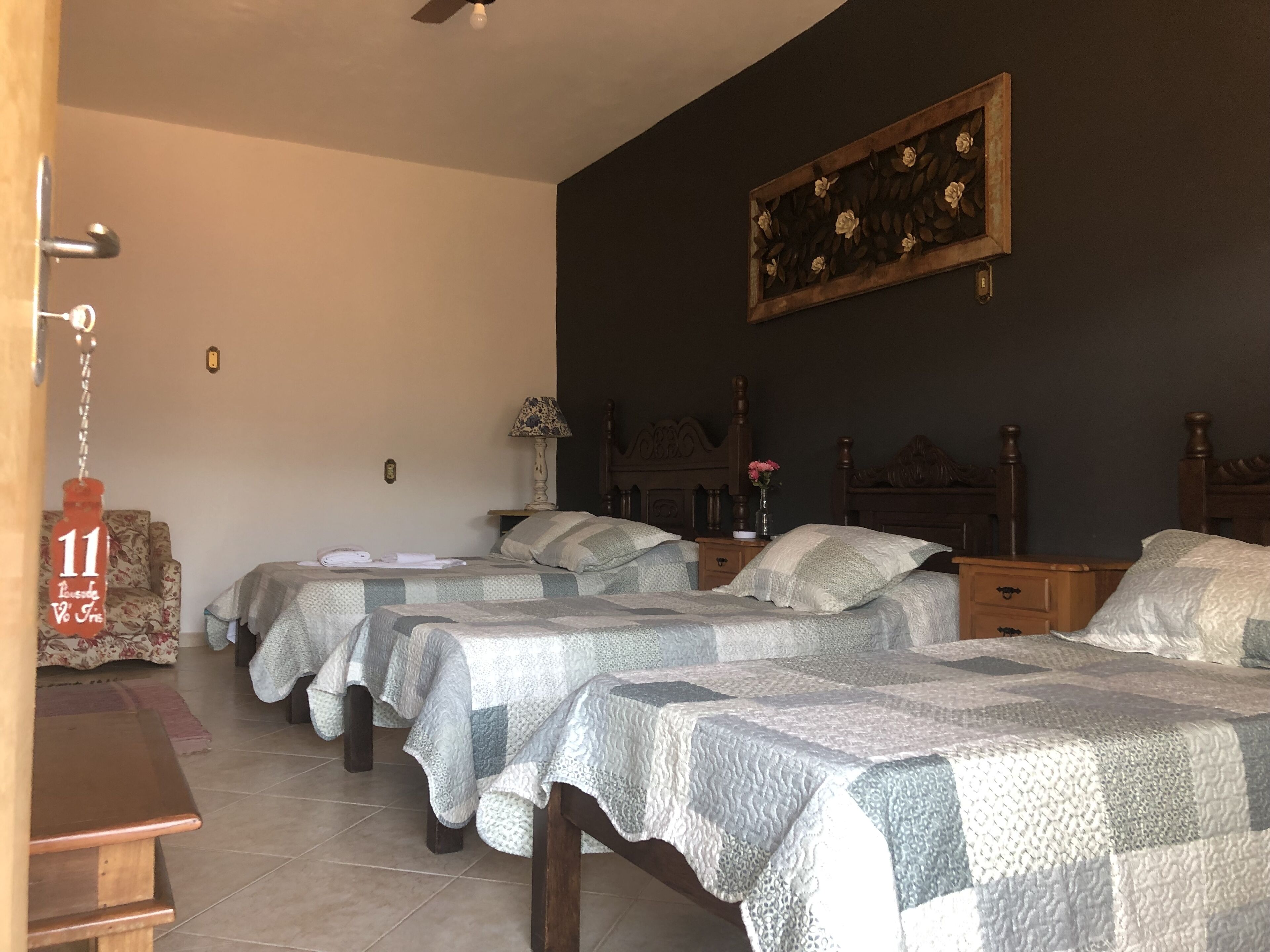 Habitación de hotel con dos camas, una mesita de noche de madera, una lámpara y una obra de arte floral en la pared.