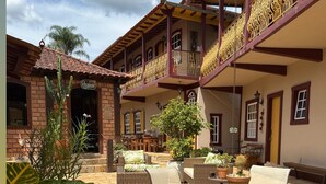 Un patio con mobiliario exterior, plantas en macetas y un edificio con balcón.