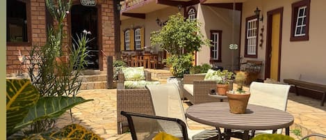Un patio con mobiliario exterior, plantas en macetas y un edificio con balcón.