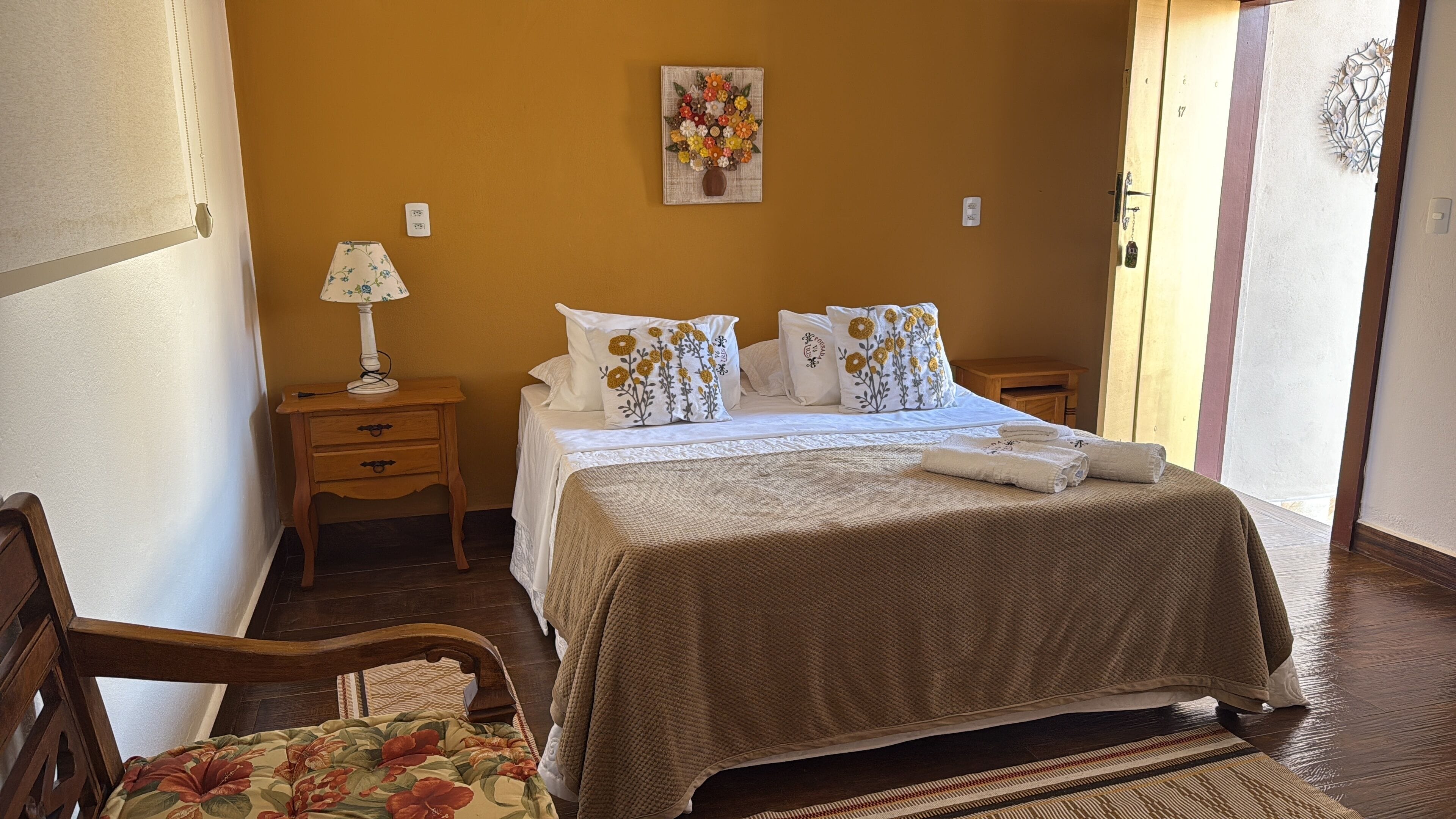 A neatly arranged bedroom with a bed, bedside tables, a lamp, and a decorative wall piece.