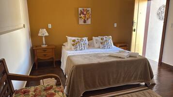 A neatly arranged bedroom with a bed, bedside tables, a lamp, and a decorative wall piece.