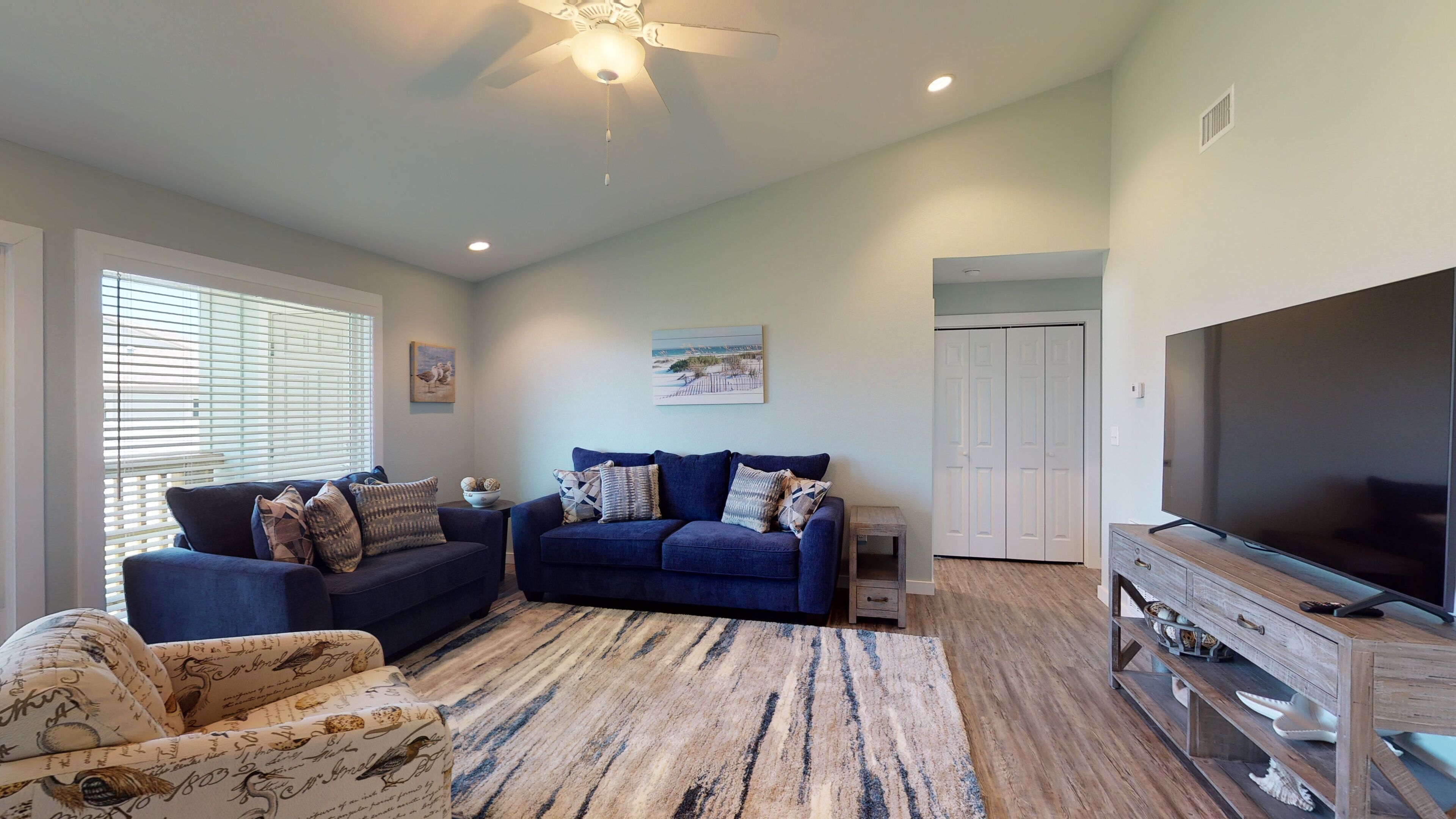 A living room with two sofas, a coffee table, a TV, and a wooden entertainment unit.