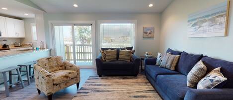 A living room with a sofa, armchair, and a dining area with a table and chairs.