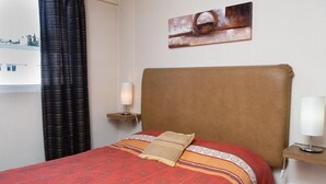 A hotel room with a bed, a headboard, a bedside table with a lamp, a wall-mounted artwork, and a window with curtains. - DEPARTMENT WITH EXCELLENT LOCATION (San Carlos de Bariloche)