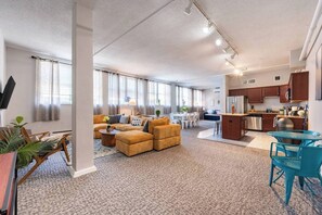 A spacious living area with a sofa set, a dining table, and a kitchen area with modern appliances.