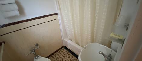 Un baño pequeño con inodoro, lavamanos y cortina de ducha.