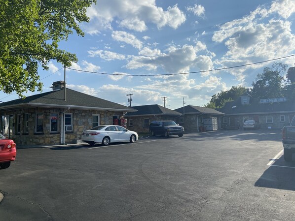 Un motel con fachada de piedra, un letrero y un estacionamiento con varios coches.