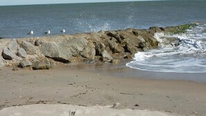 Uma costa rochosa com ondas quebrando na praia.