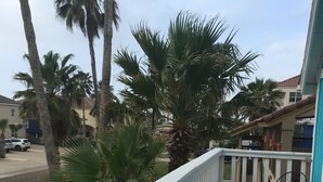 A wooden deck with a white railing, two blue chairs, and a table. - SUPER LOCATION, MIDDLE OF THE ISLAND (South Padre Island)