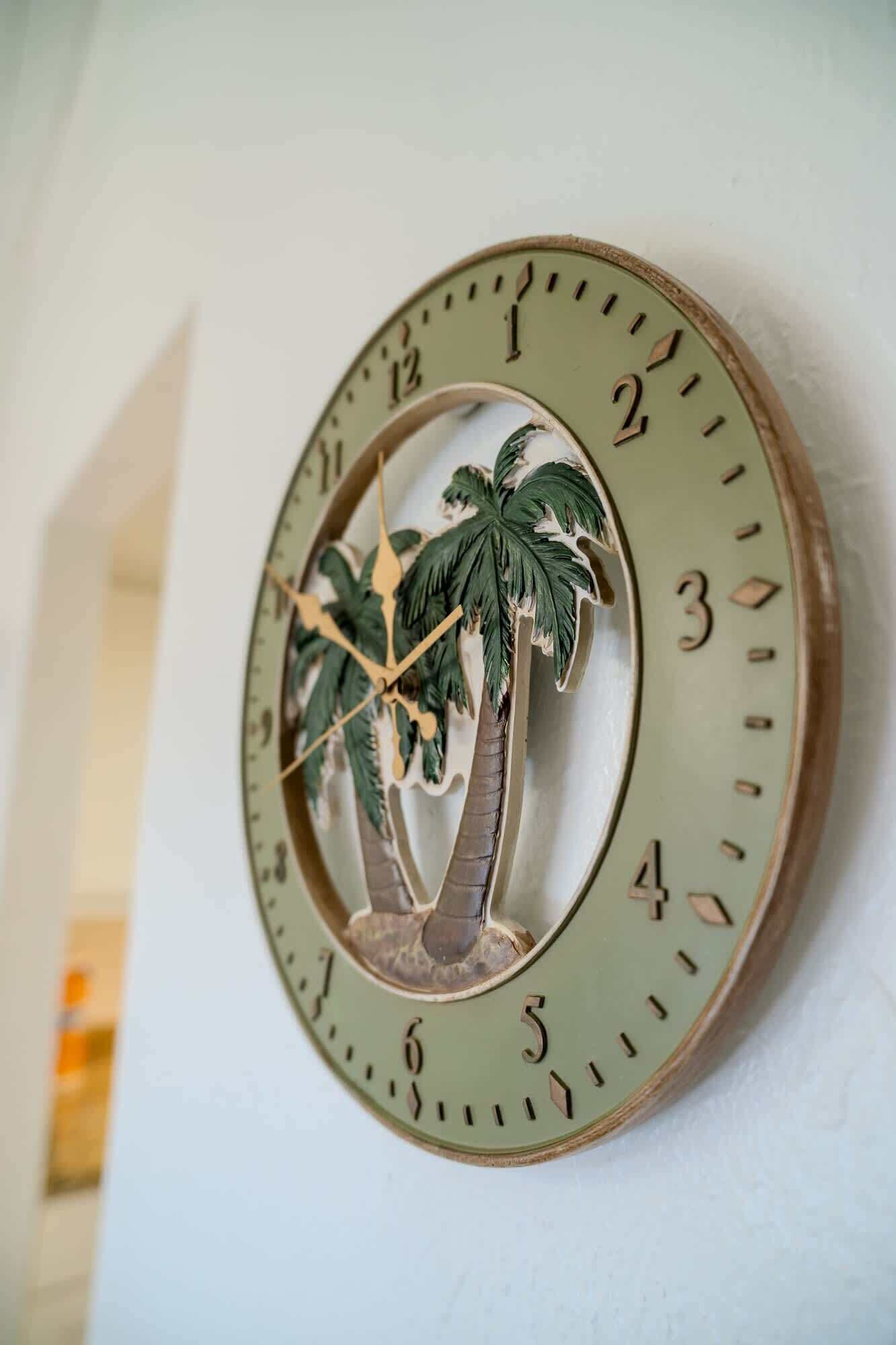 Een wandklok met een tropisch palm ontwerp.