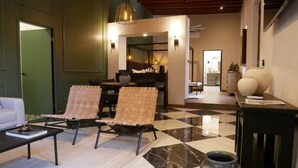 A spacious living area with a checkered floor, two cushioned chairs, a coffee table, and a large vase. - Hotel Hostal El Farol (Parras)