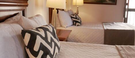 A hotel room with two beds, a nightstand, two lamps, and a painting on the wall.