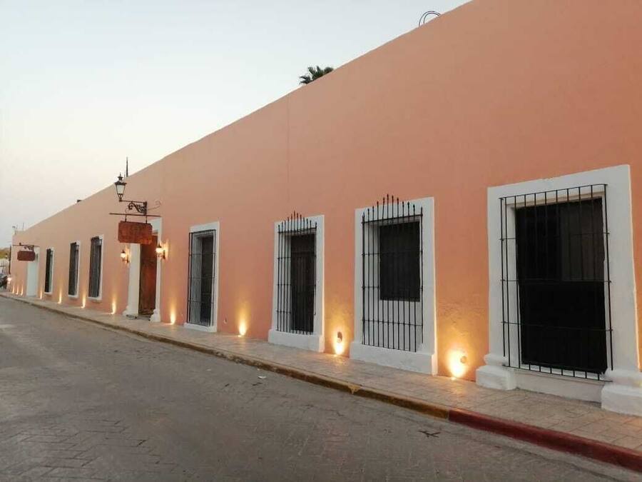 A row of buildings with uniform architecture, featuring evenly spaced windows with metal bars, a consistent color scheme, and a paved street in the foreground.