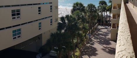 A multi-story building with a view of the beach and palm trees.