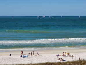 A beach with people walking, sunbathing, and a sailboat in the water. - On Siesta Key beach  , condo w/ heated pool, w/ beautiful 4th floor view (Sarasota)